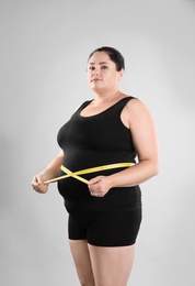 Photo of Fat woman with measuring tape on grey background. Weight loss