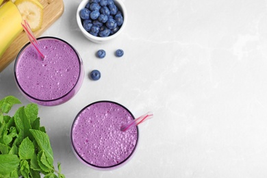 Flat lay composition with delicious blueberry smoothie on light marble table. Space for text