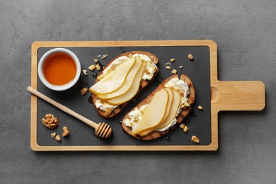 Photo of Toasted bread with tasty cream cheese and pear on gray table, flat lay