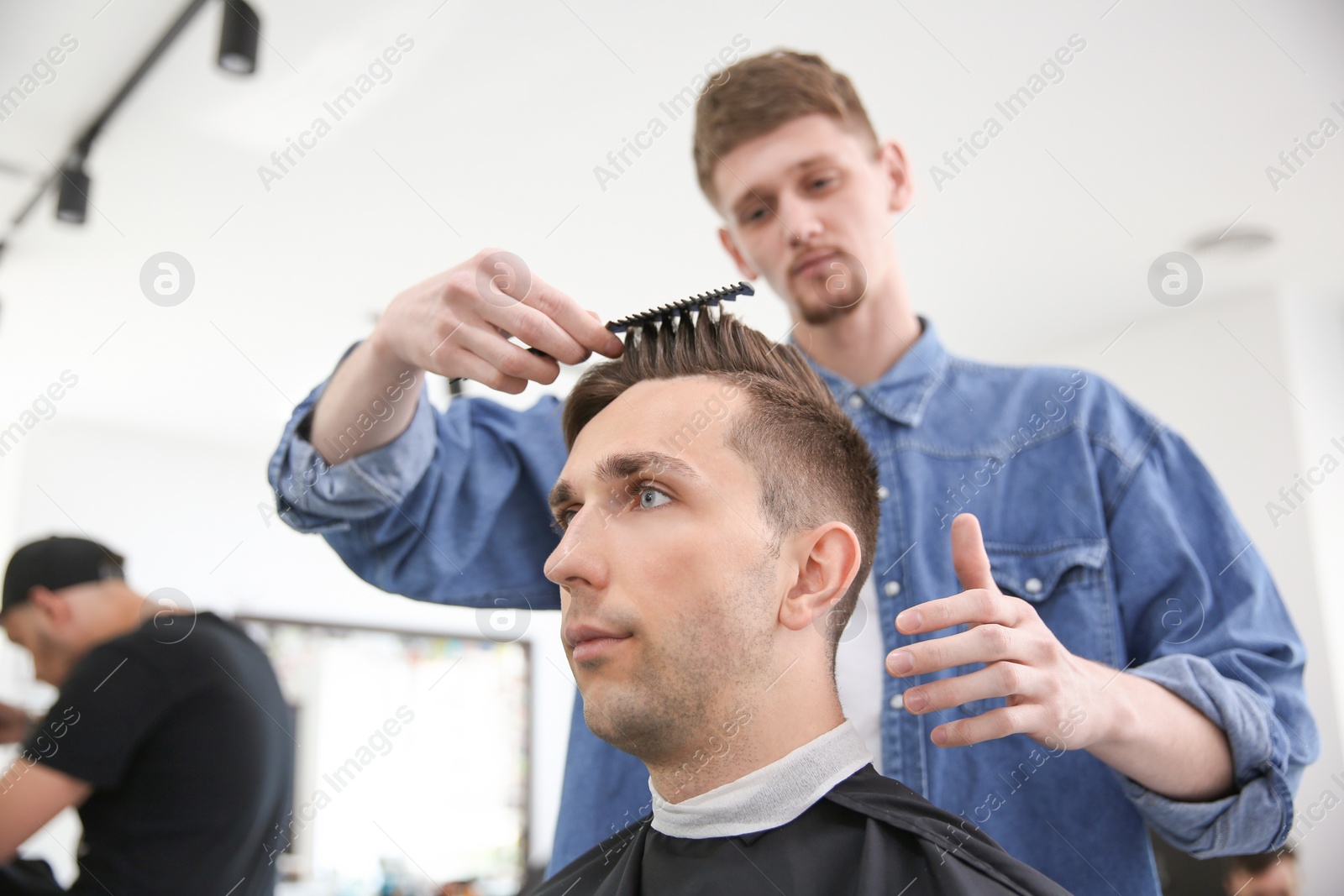 Photo of Professional barber working with client in hairdressing salon. Hipster fashion