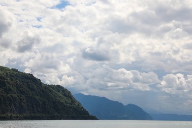 Picturesque view of mountains and sea under beautiful sky with fluffy clouds