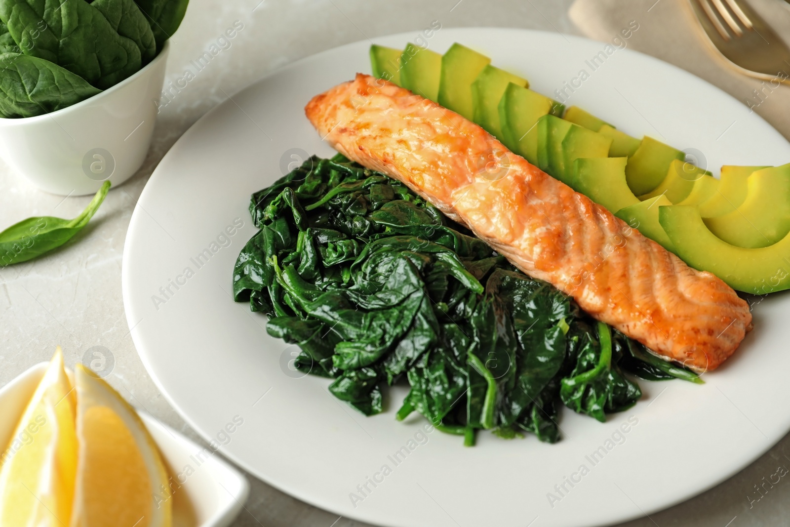 Photo of Tasty salmon with spinach and avocado on light table, closeup