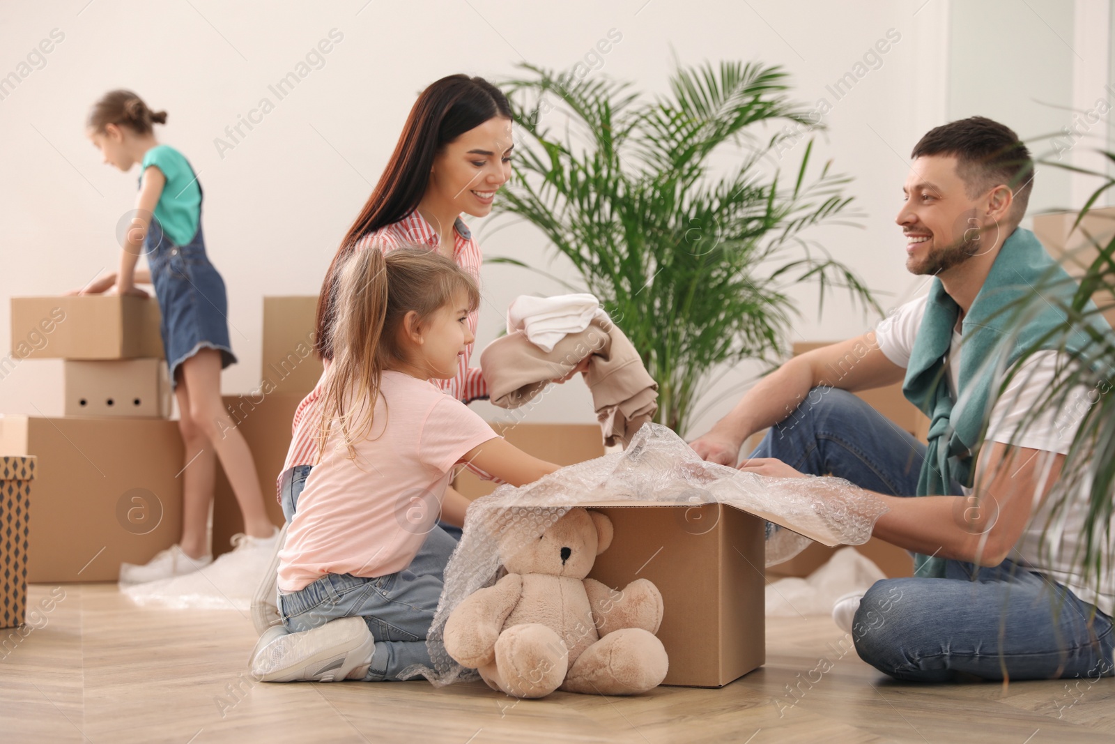 Photo of Happy family unpacking moving boxes in new house