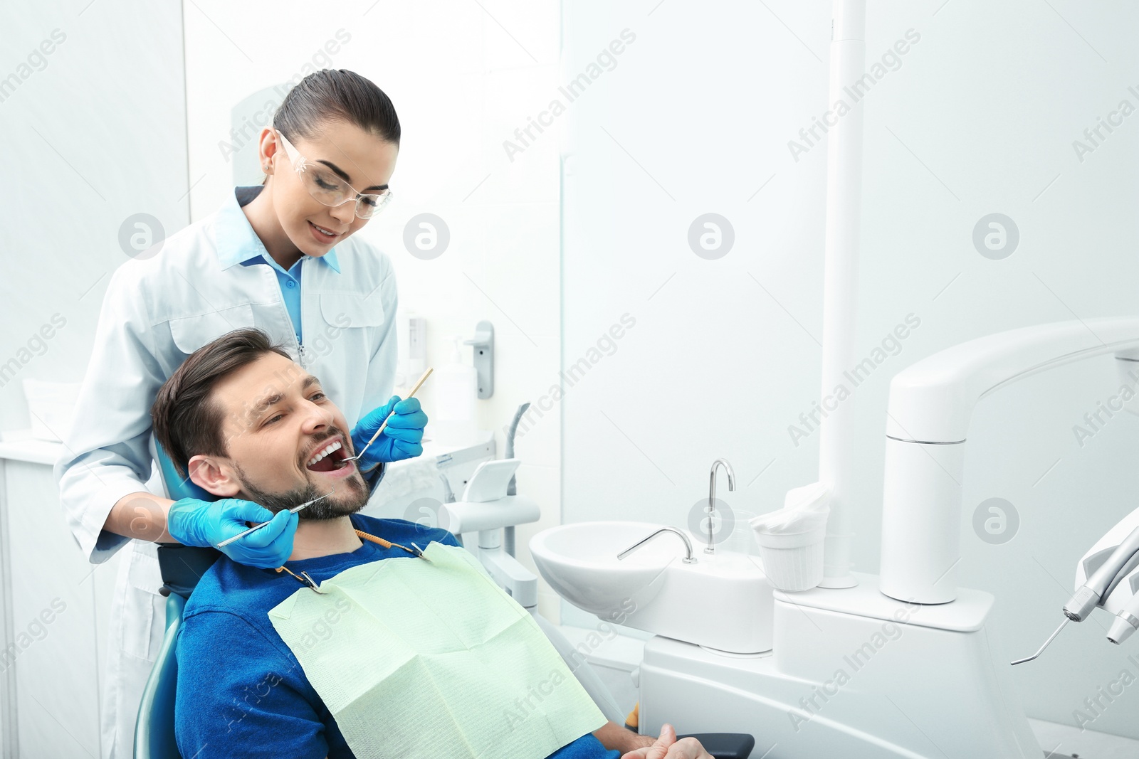 Photo of Professional dentist working with patient in modern clinic. Space for text