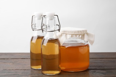 Photo of Homemade fermented kombucha in glass jar and bottles on wooden table