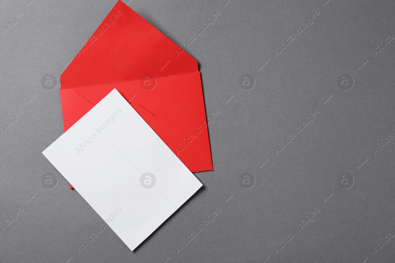 Photo of Blank sheet of paper and letter envelope on grey background, top view. Space for text