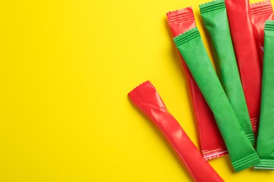 Photo of Different sticks of sugar on yellow background, flat lay. Space for text