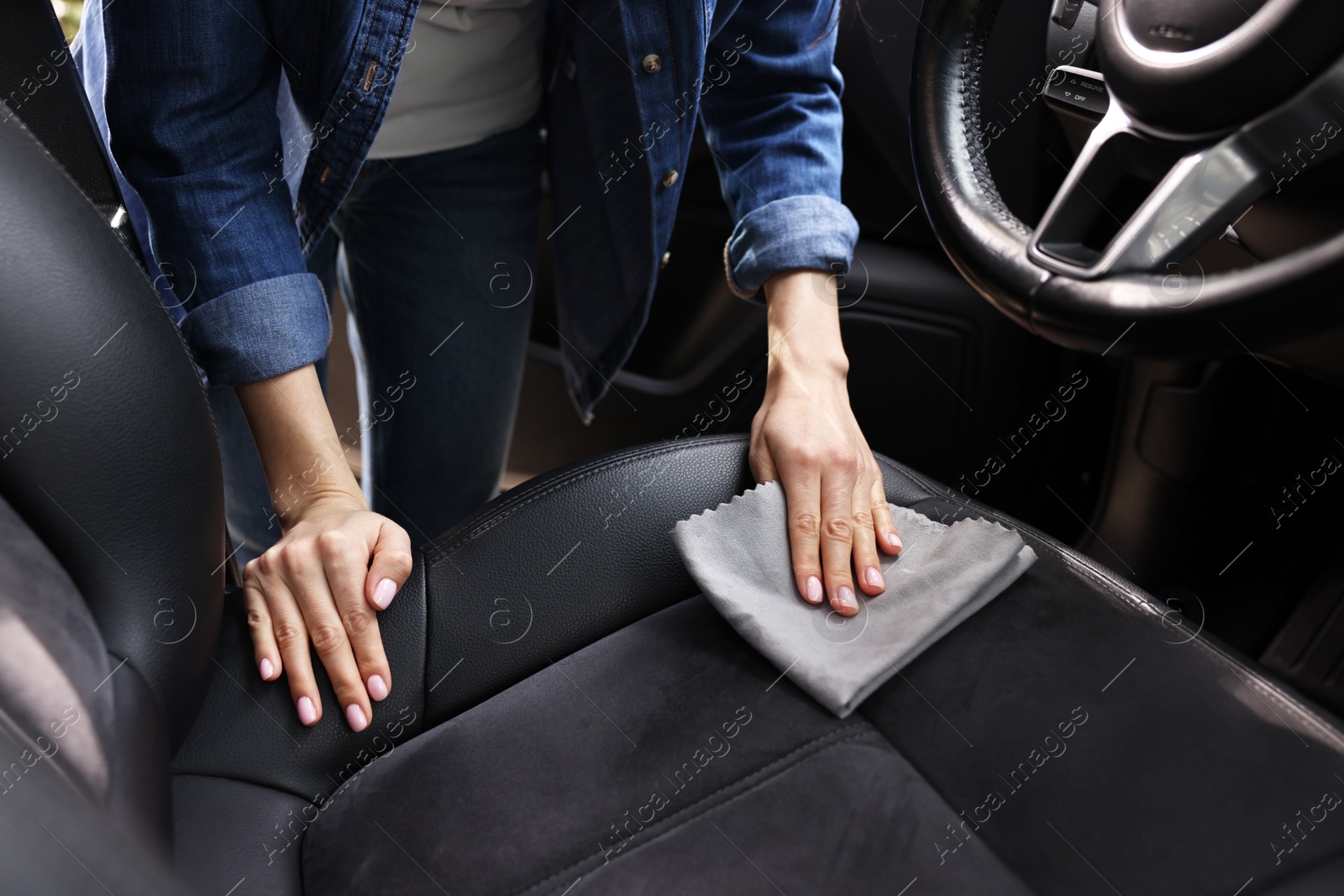 Photo of Woman wiping her modern car with rag, closeup