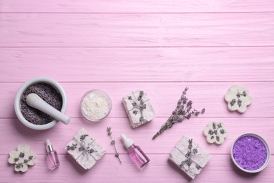Photo of Flat lay composition with hand made soap bars and lavender flowers on pink wooden table, space for text