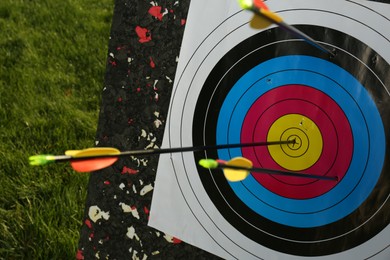 Photo of Arrows in archery target on green grass outdoors, closeup