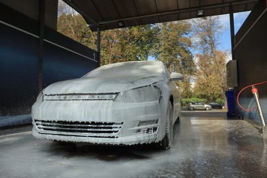 Auto with cleaning foam at outdoor car wash