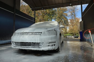 Photo of Auto with cleaning foam at outdoor car wash