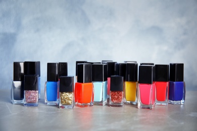 Photo of Bottle of bright nail polish on table against color background. Space for text