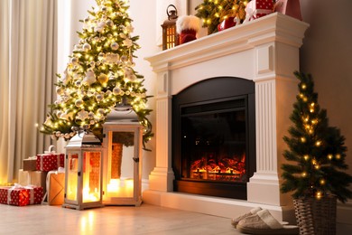 Photo of Beautiful fireplace, Christmas tree and other decorations in living room. Interior design