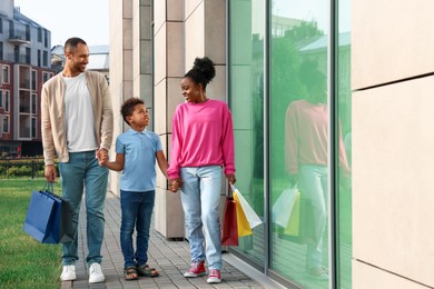 Family shopping. Happy parents and son with colorful bags near mall outdoors