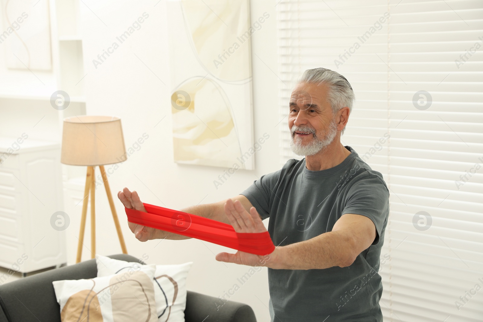 Photo of Senior man doing exercise with fitness elastic band at home