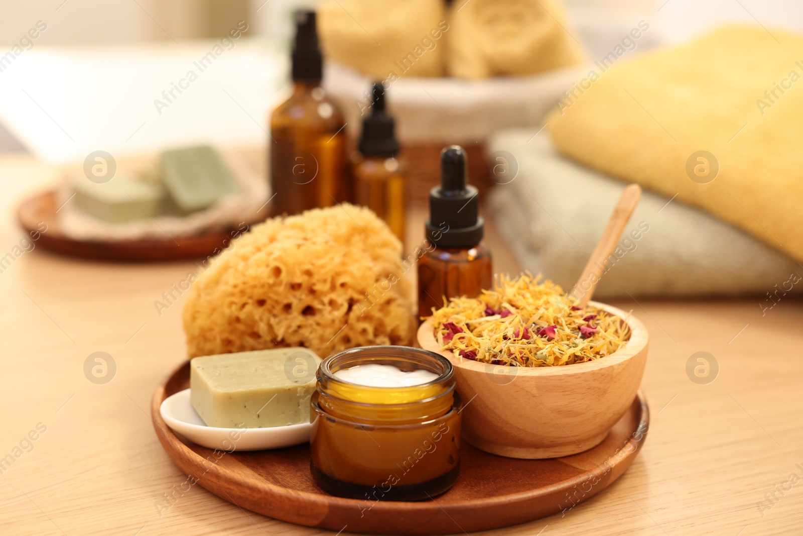 Photo of Dry flowers, loofah, soap bar, bottle of essential oil and jar with cream on wooden table. Spa time