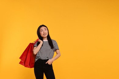 Photo of Smiling woman with shopping bags on yellow background. Space for text