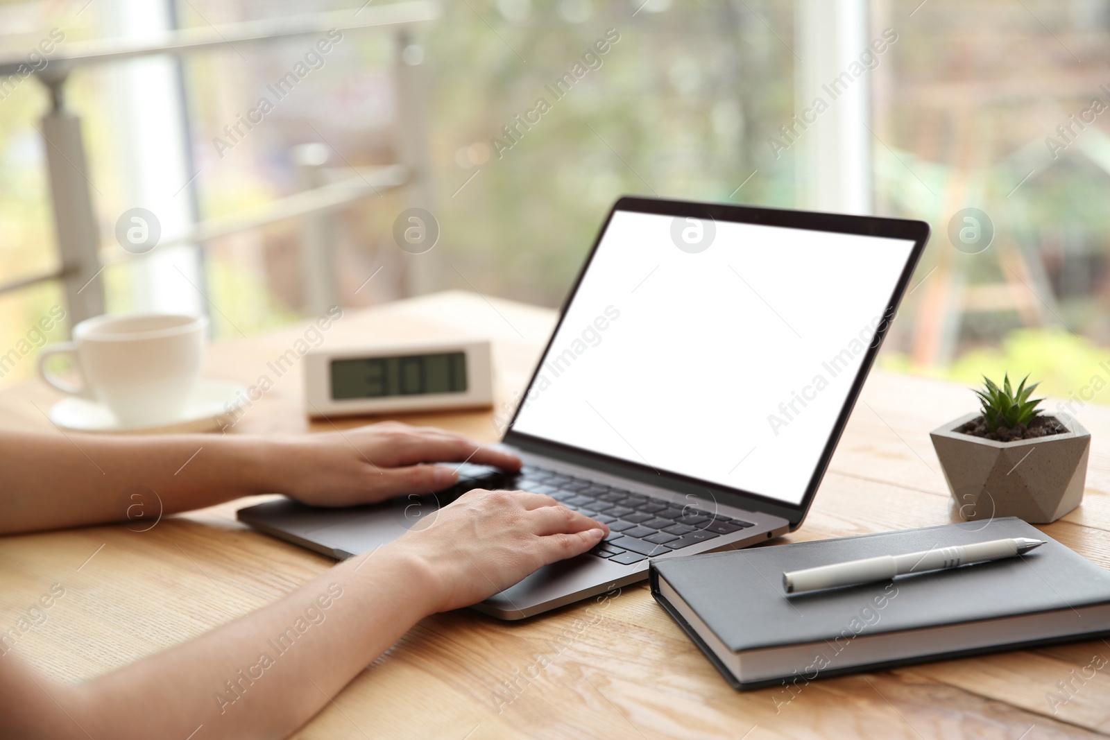 Photo of Woman working with modern laptop at wooden table, closeup