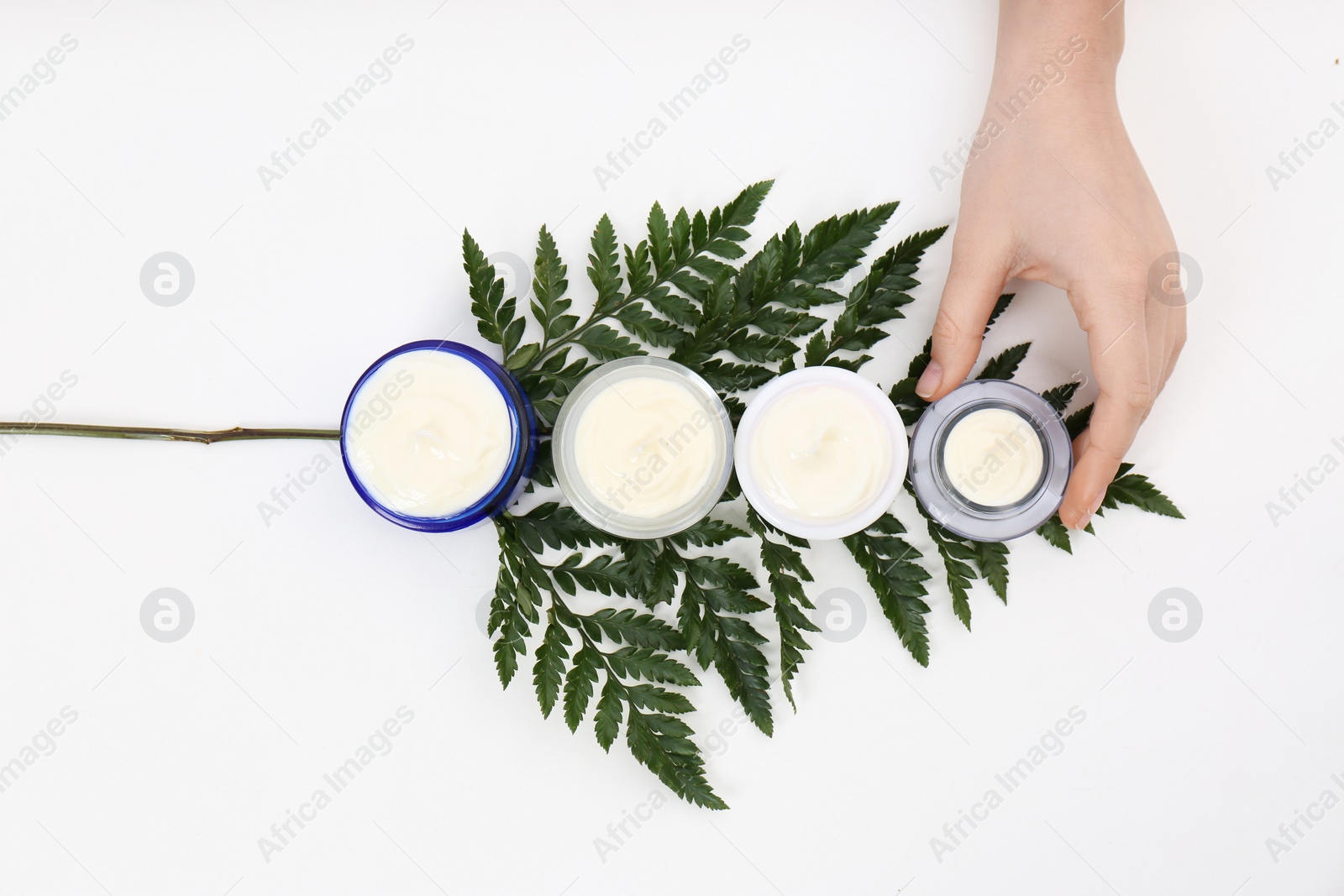 Photo of Female dermatologist with jars of skin care products on white background, top view