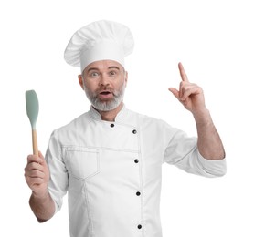 Surprised chef in uniform with spatula pointing at something on white background