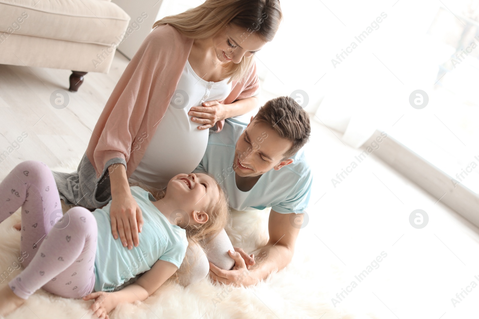 Photo of Young pregnant woman with her family at home