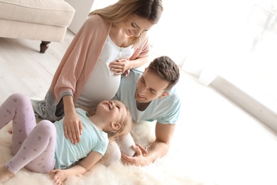 Young pregnant woman with her family at home