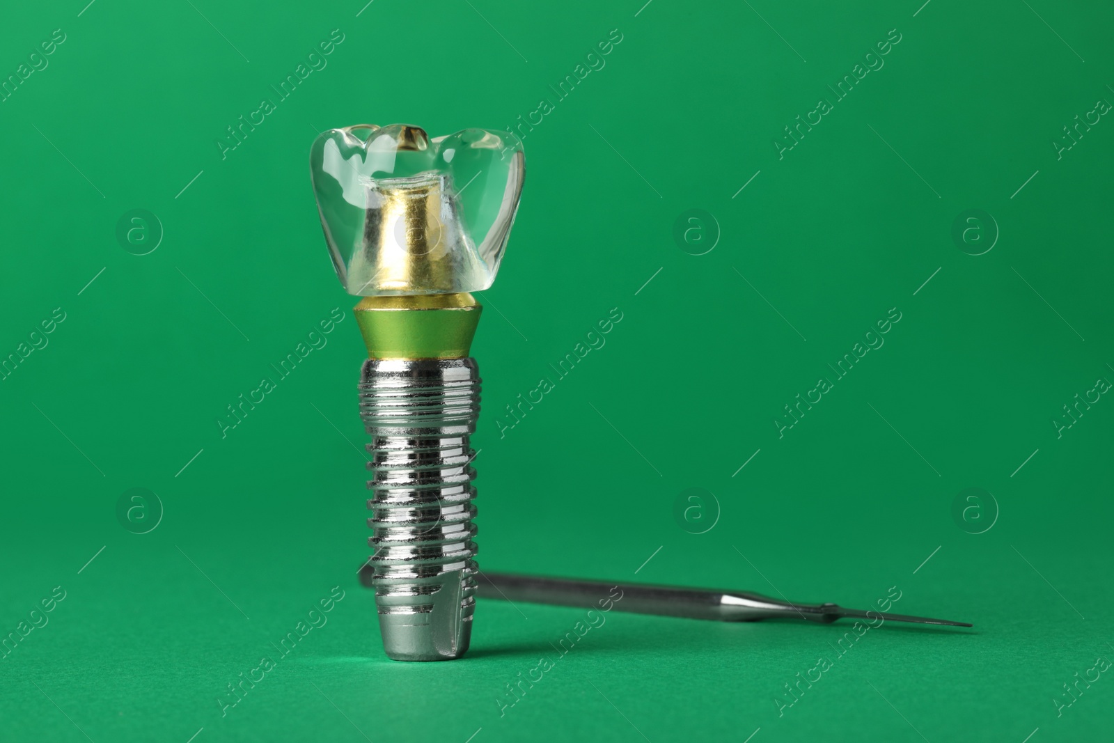 Photo of Educational model of dental implant near medical tool on green background. Space for text