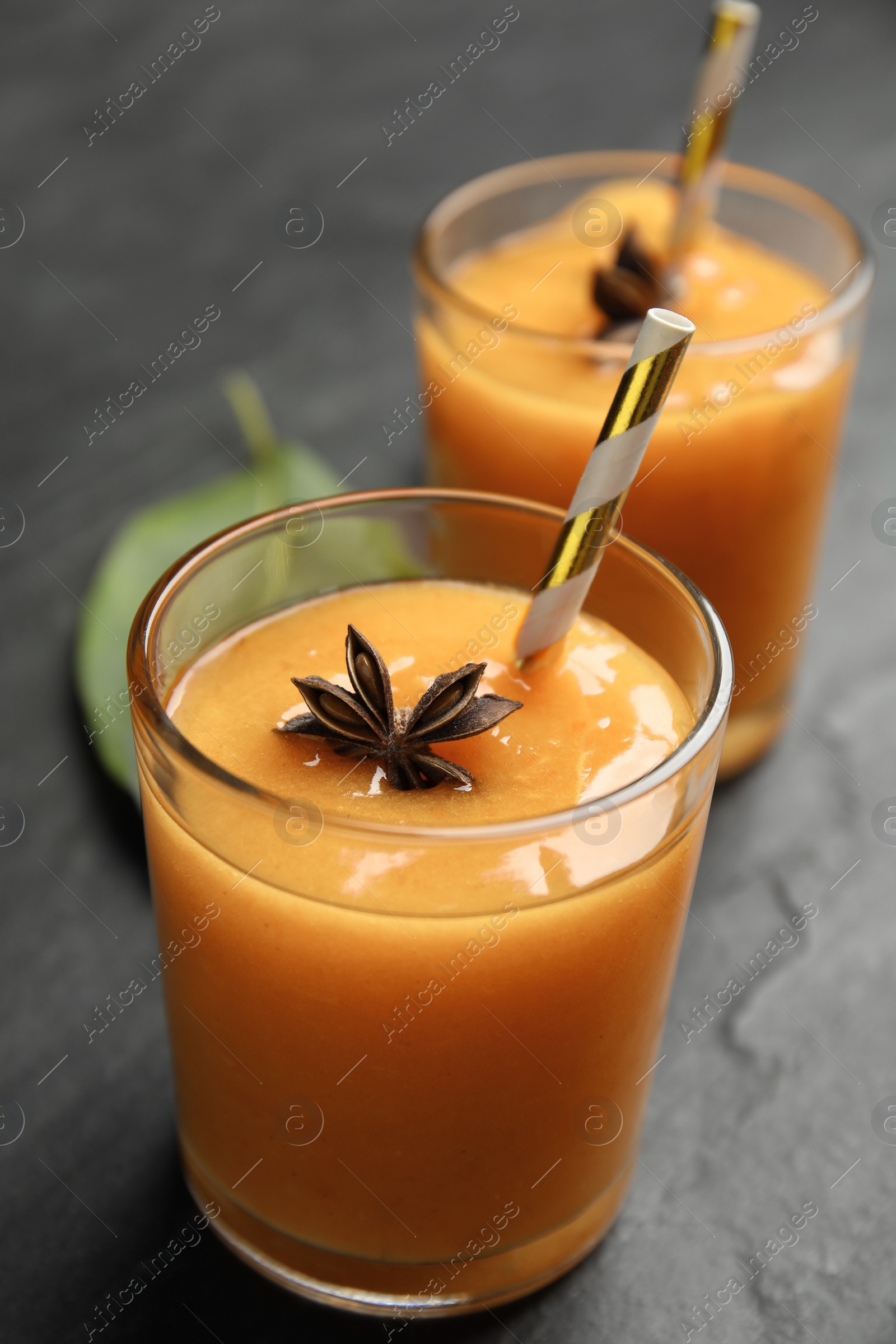 Photo of Tasty persimmon smoothie with anise on black table, closeup