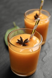 Tasty persimmon smoothie with anise on black table, closeup