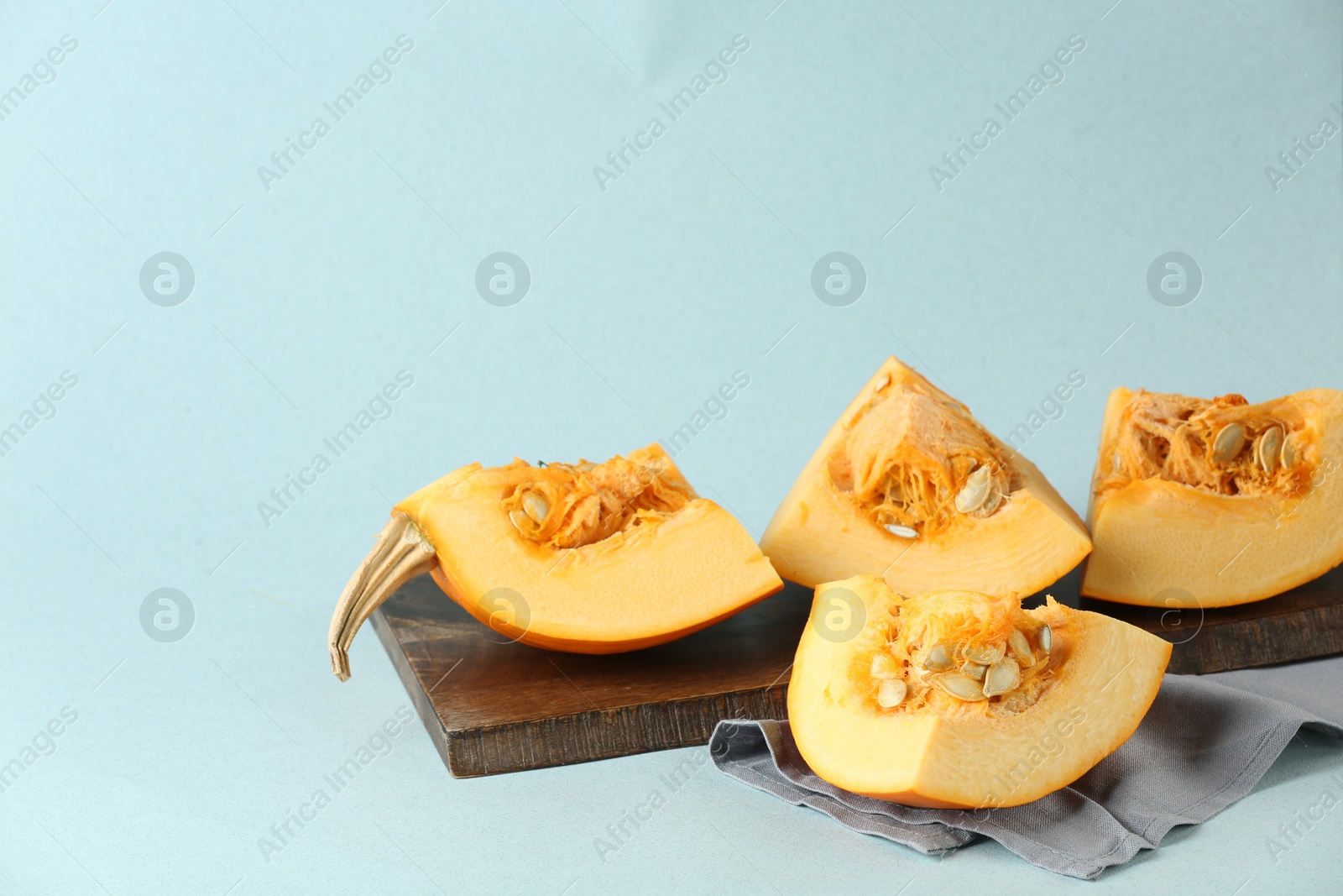 Photo of Cut fresh ripe pumpkin on light blue background, space for text