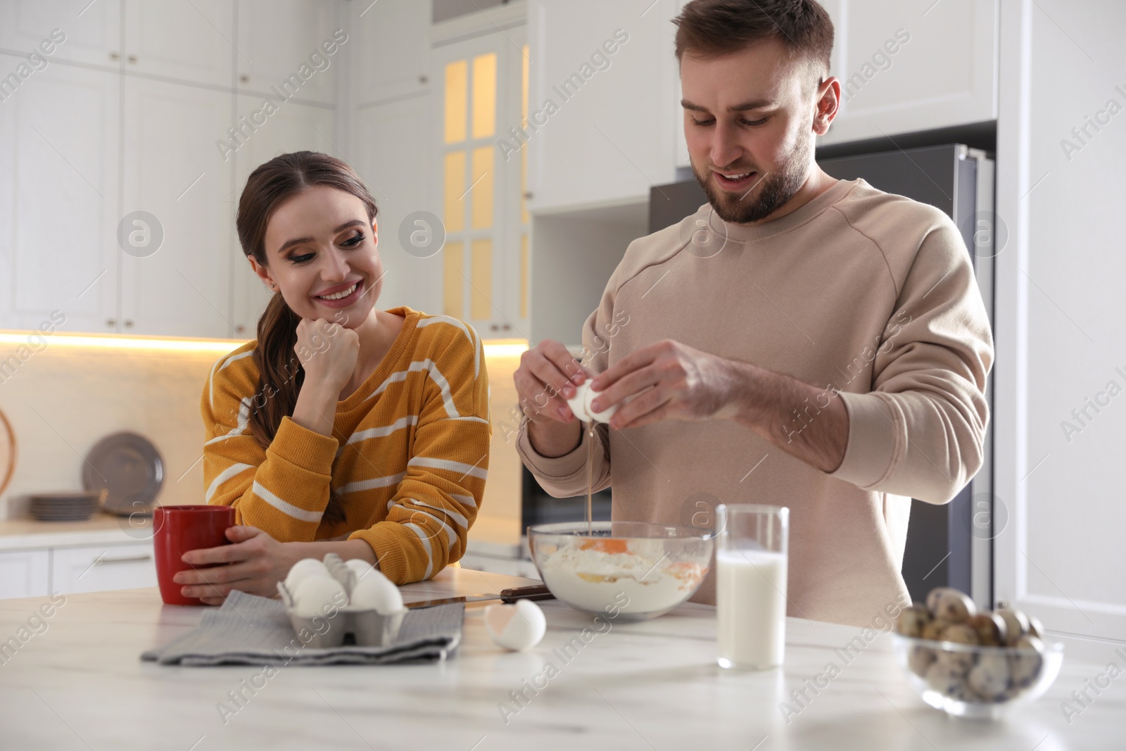 Photo of Lovely young couple cooking dough together in kitchen