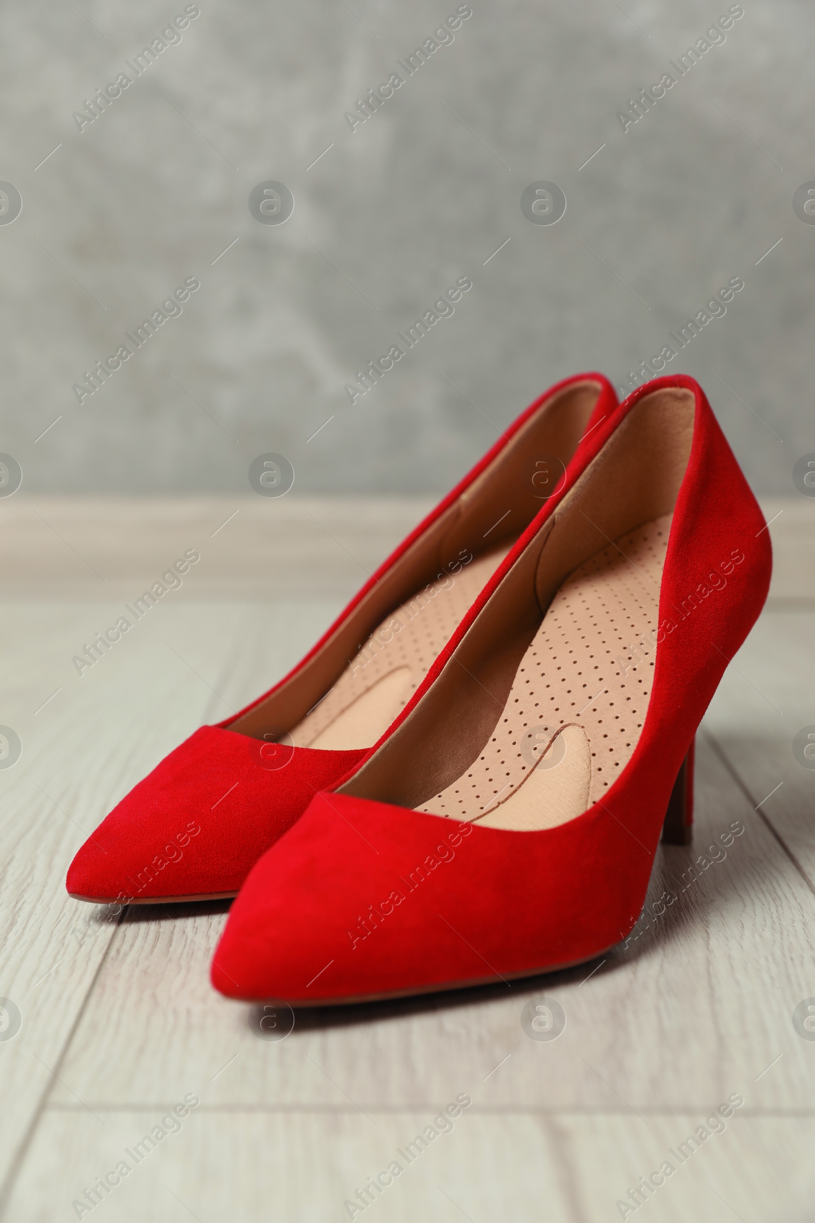 Photo of Orthopedic insoles in high heel shoes on floor, closeup