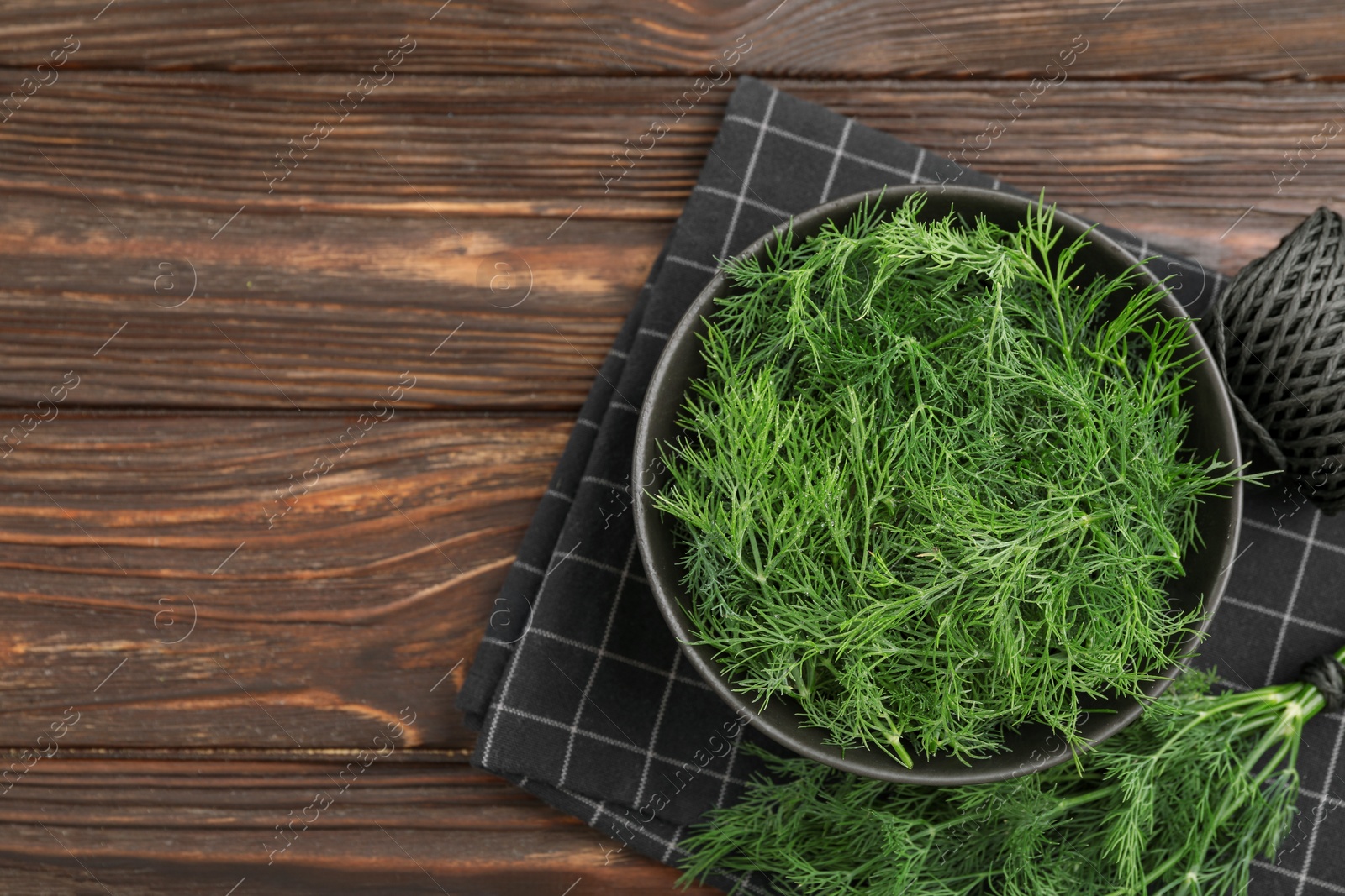 Photo of Bowl of fresh dill on wooden table, flat lay. Space for text