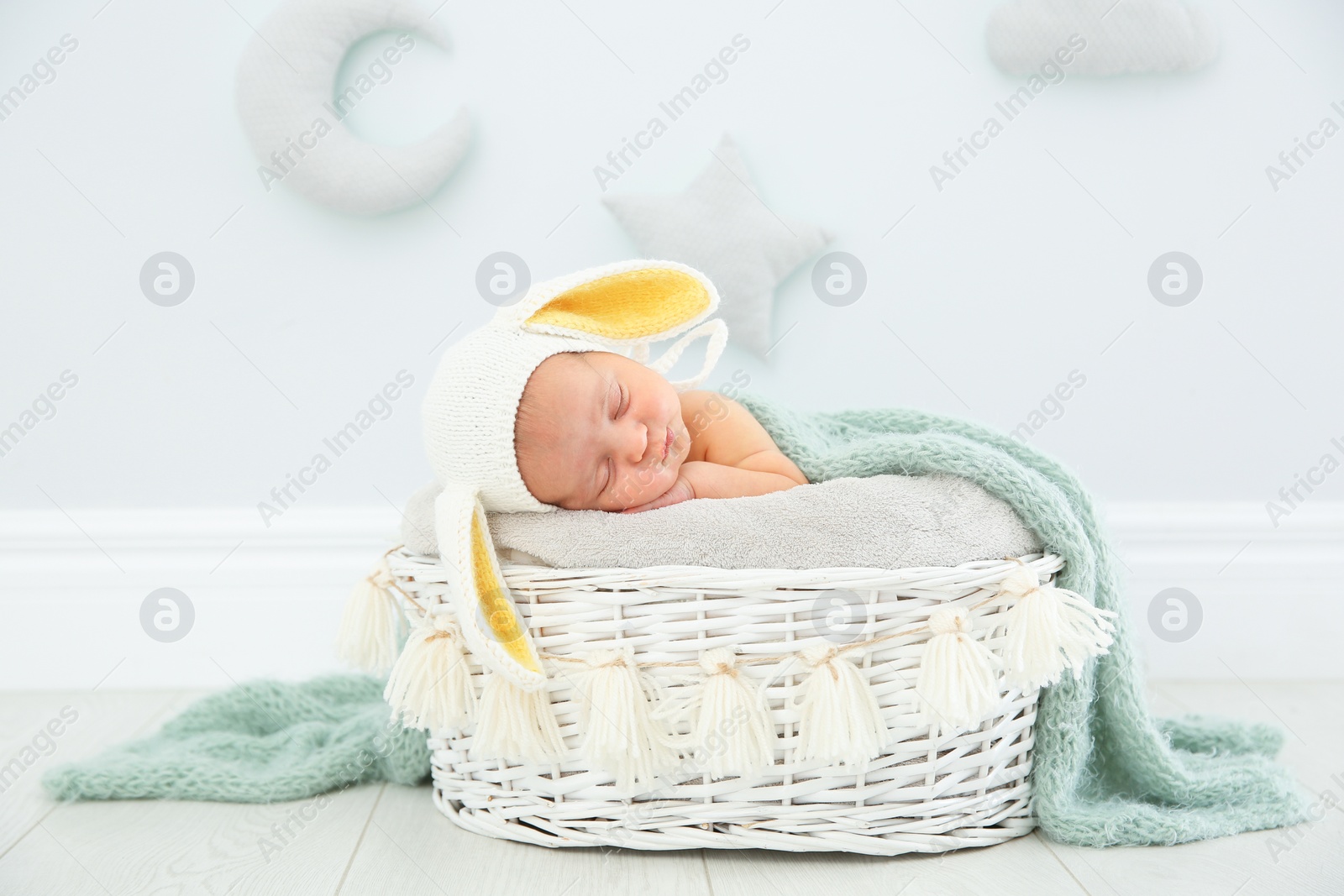 Photo of Adorable newborn child wearing bunny ears hat in baby nest indoors