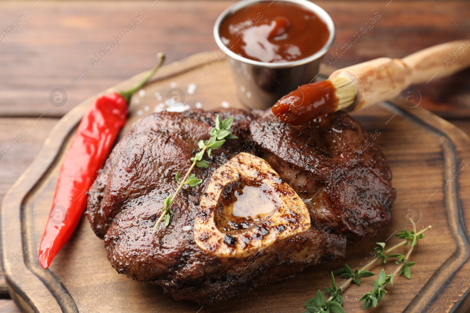 Photo of Delicious roasted beef meat served with sauce and spices on wooden table, closeup