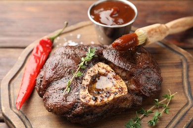 Delicious roasted beef meat served with sauce and spices on wooden table, closeup