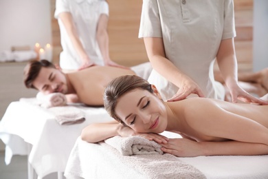 Photo of Romantic young couple enjoying back massage in spa salon