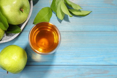 Photo of Glass of fresh juice and apples on light blue wooden table, flat lay. Space for text