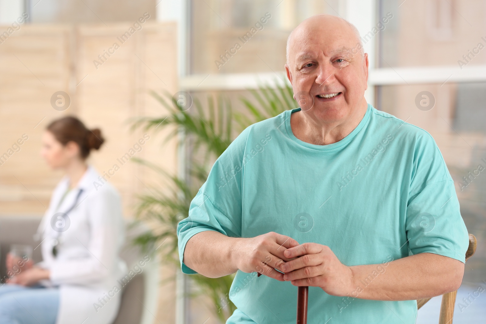 Photo of Elderly man with cane in nursing home, space for text. Assisting senior generation