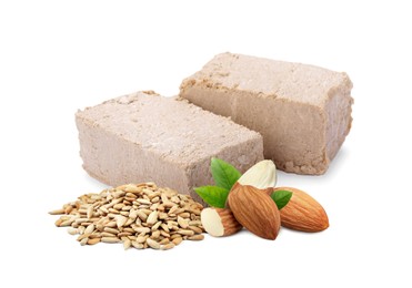 Image of Tasty halva, peeled sunflower seeds, almonds and green leaves isolated on white