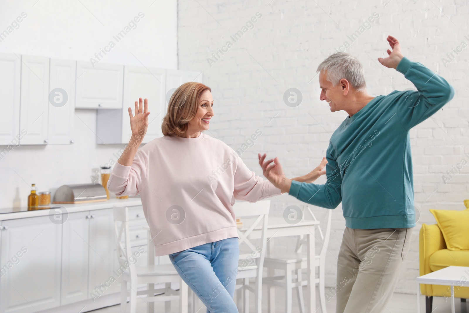 Photo of Happy senior couple dancing together in kitchen