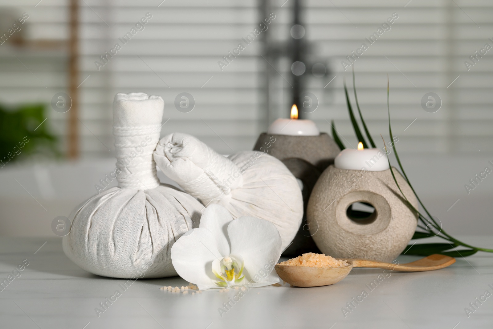 Photo of Composition with spa products, plumeria flower and burning candles on white table indoors