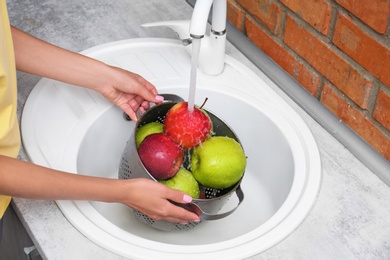 Photo of Woman washing fresh apples in kitchen sink, closeup