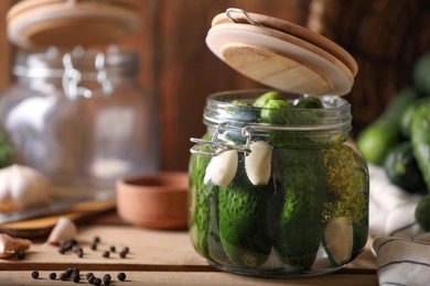 Photo of Glass jar with fresh cucumbers and other ingredients on wooden table. Canning vegetable