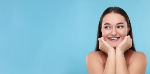 Image of Smiling woman with braces on light blue background. Banner design with space for text