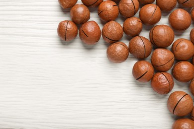 Delicious Macadamia nuts on white wooden table, flat lay. Space for text