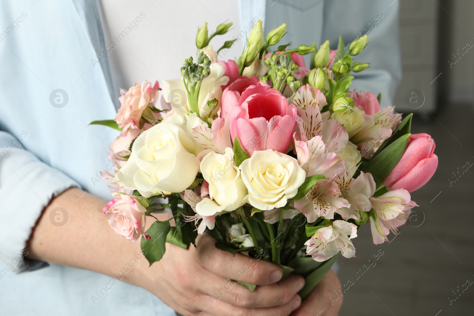 Photo of Man holding bouquet of beautiful flowers indoors, closeup