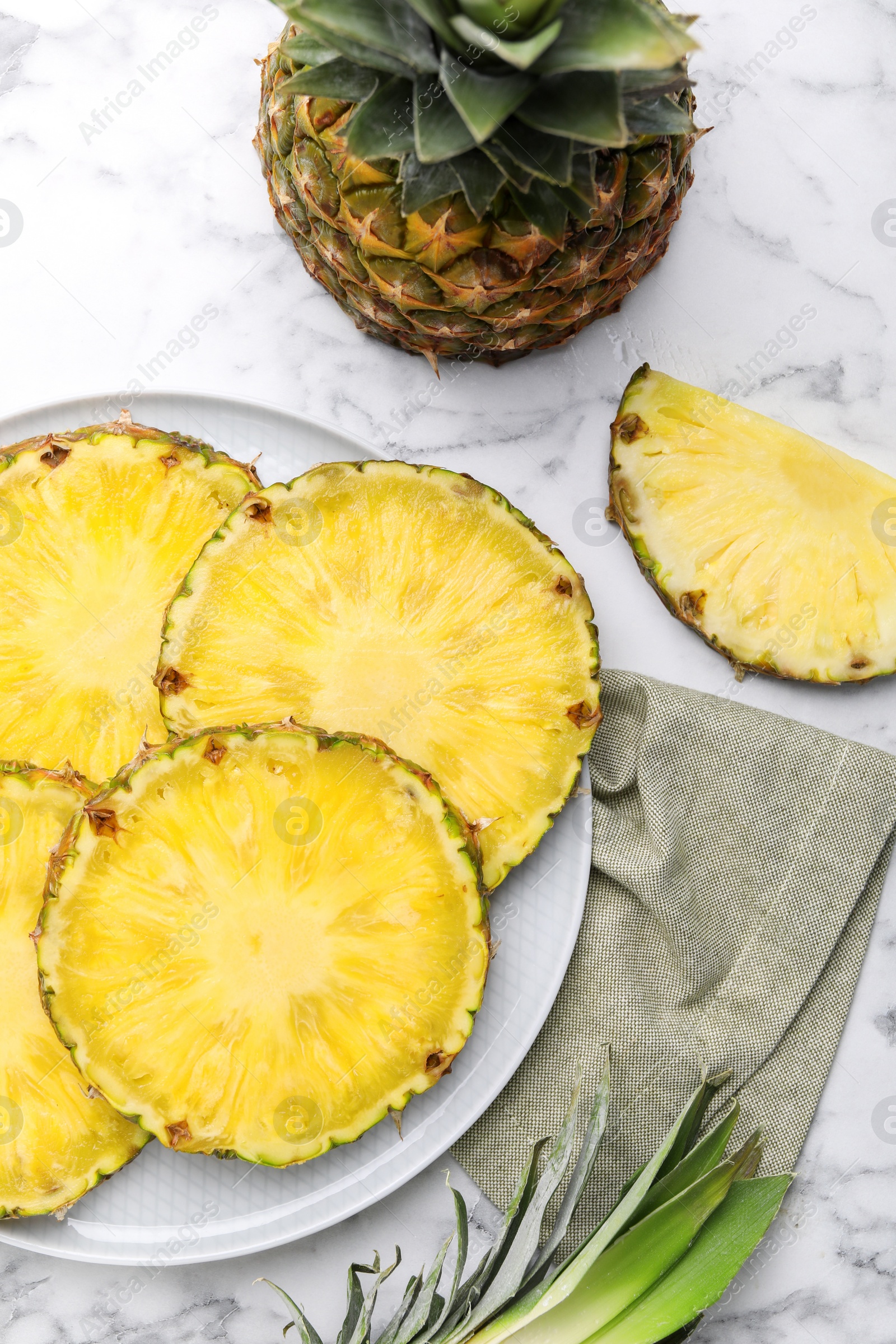 Photo of Slices of tasty ripe pineapple on white marble table, flat lay