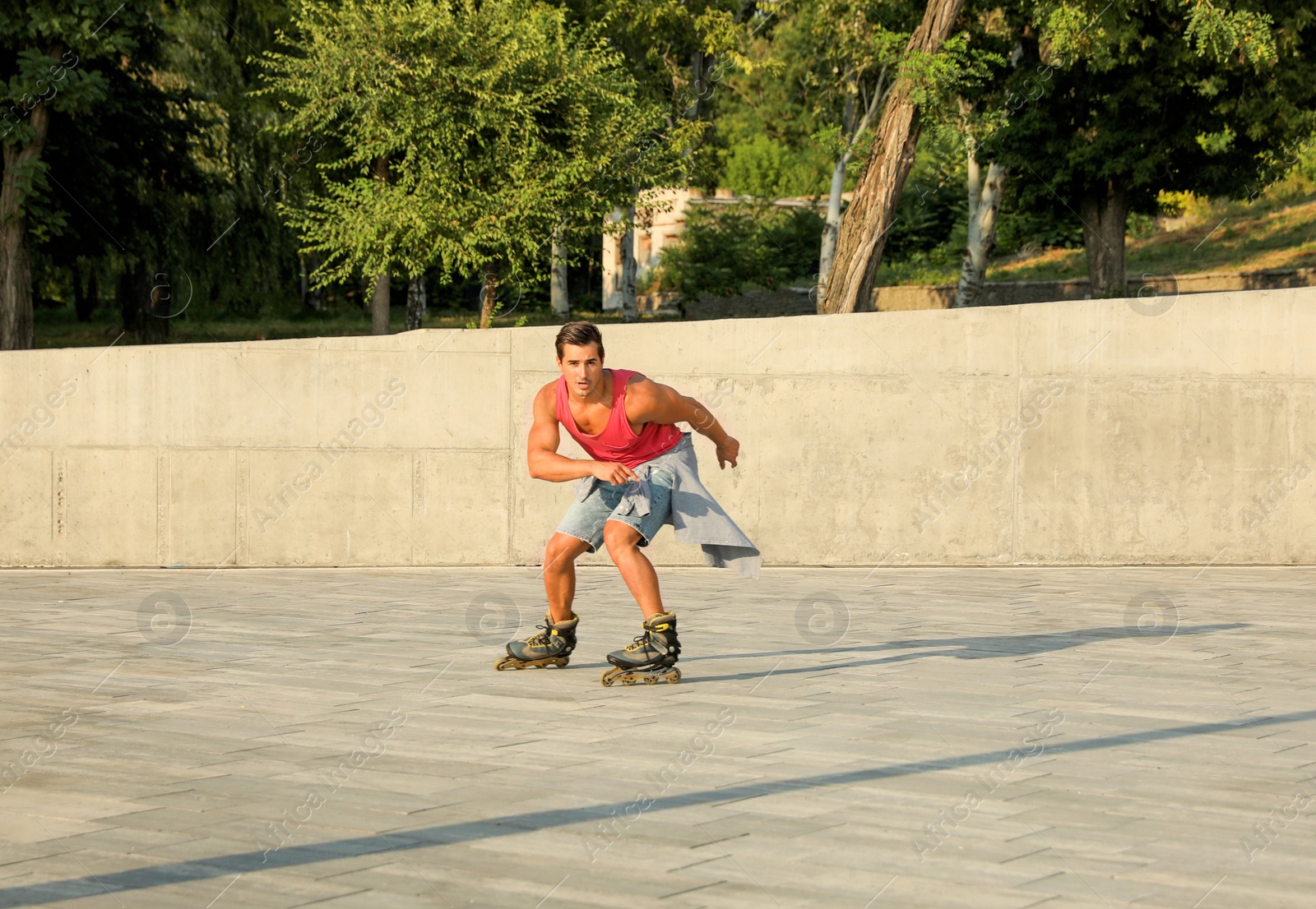 Photo of Handsome young man roller skating on city street, space for text